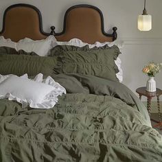 the bed is made with green linens and white ruffles on it's headboard