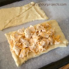 two uncooked pizza doughs sitting on top of a baking sheet with chicken and cheese