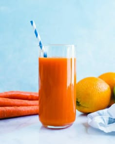 an orange juice in a glass next to some carrots