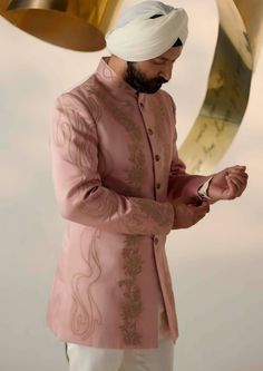 a man with a turban standing in front of a golden bell and looking at his cell phone