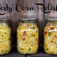 three jars filled with corn sitting on top of a wooden table