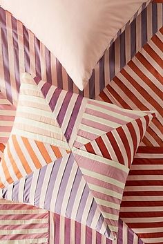 a bed with colorful striped pillows on top of it and a white pillow in the middle