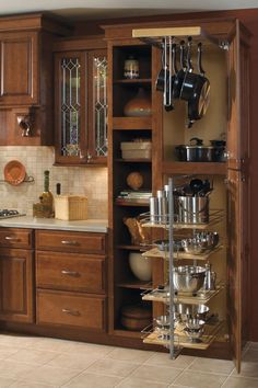 an open cabinet with pots and pans on it in the middle of a kitchen