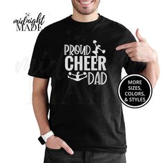 Looking for a unique cool Cheerleader Dad gift? This Midnight Made® Proud Cheer Dad T-shirt Tee is sure to delight! This sport parent shirt is a perfect Birthday, Big Game, Meet, or Competition gift for a Cheerleader Dad. This under 30 dollars novelty graphic Cheer Dad Tshirt Top is also a great present or gift idea for Christmas, Hanukkah, or other Holidays. T-SHIRT DETAILS:  Made to order and individually printed directly on the item (NOT an iron-on decal) on a comfortable, high quality, 100% cotton (fiber content may vary depending on color) short-sleeved T-Shirt. The back is blank, unless pictured otherwise. Multiple colors (light designs on dark shirts, dark designs on light shirts, and high-contrast full-color designs print well on either dark or light shirts) and sizes (Infant/Baby, Graphic Tee T-shirt For Cheerleading, Black T-shirt With Team Name For Cheerleading, Black Crew Neck T-shirt For Cheerleading, Cheerleading Short Sleeve T-shirt With Screen Print, Short Sleeve Cheerleading T-shirt With Screen Print, Short Sleeve T-shirt With Screen Print For Cheerleading, Father's Day Team Spirit Graphic T-shirt, Black Sports Fan T-shirt For Cheerleading, Black Fan Apparel T-shirt For Cheerleading