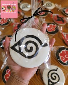 a person holding up some decorated cookies in front of a bunch of other treats on a table