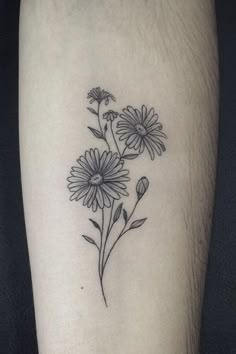 a black and white flower tattoo on the left leg, with daisies in it