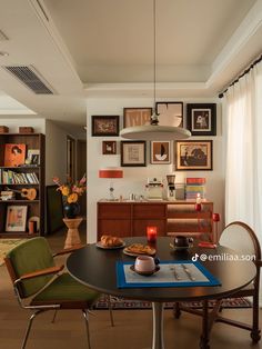 a dining room table and chairs with pictures on the wall