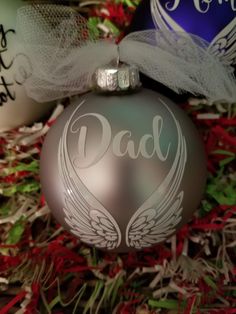 an ornament with the word dad written on it and two angel wings attached to it