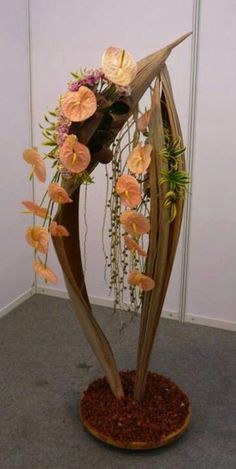 a vase filled with flowers on top of a wooden stand in front of a wall