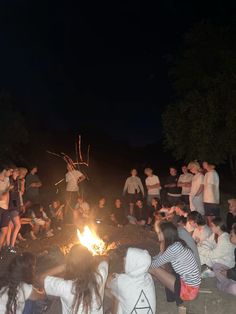 a group of people sitting around a campfire at night