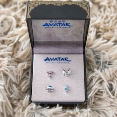 two pairs of earrings sitting in a box on top of a carpeted floor next to each other