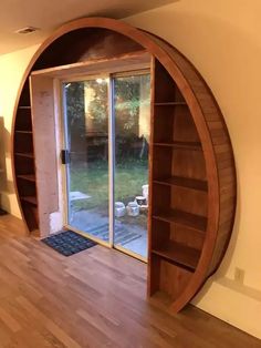 a room that has a book shelf in the middle of it and an open door to another room