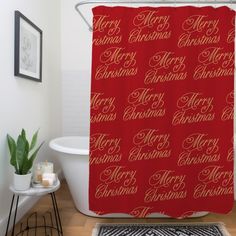 a red shower curtain with merry christmas scripting on it in a white bath room