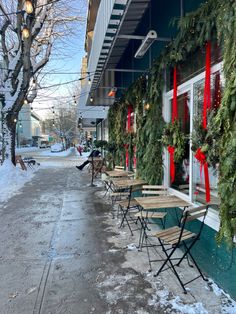 a row of tables sitting outside of a building covered in christmas wreaths and red bows