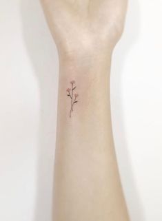 a woman's wrist with a small flower tattoo on the left side of her arm