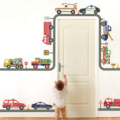 a little boy standing in front of a door with cars and trucks painted on it