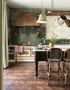 a kitchen with wooden floors and an island in the middle, surrounded by hanging lights