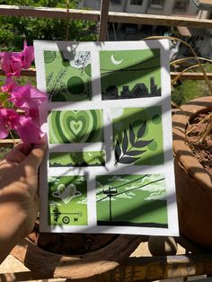 a person holding up a piece of paper with pictures on it and pink flowers in the foreground