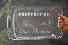 a person holding up a glass tray with the words property of louis simons on it