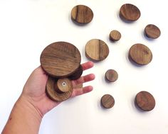 a hand is holding several wooden discs on a white surface with other wood circles around them