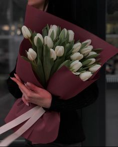 a woman holding a bouquet of white tulips