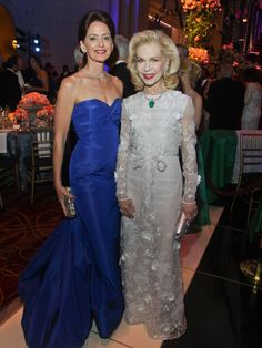 two women standing next to each other in formal wear