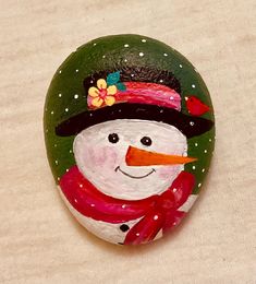 a painted rock with a snowman wearing a hat and scarf