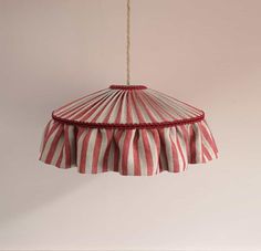 a red and white striped lamp shade hanging from a string on a wall in a room