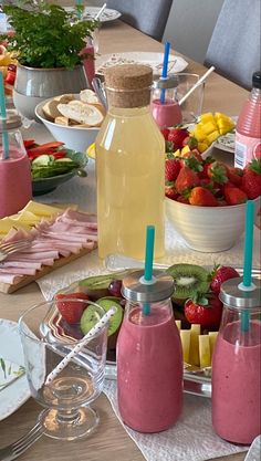 a table filled with fruit and drinks on top of a wooden table covered in plates