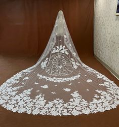 a wedding veil is sitting on the floor in front of a brown wall with white flowers