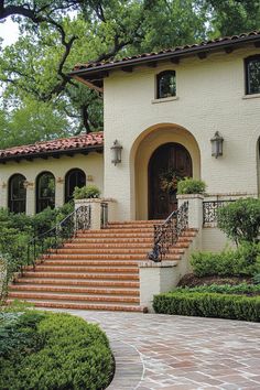 a house with steps leading up to the front door and landscaping around it, surrounded by greenery