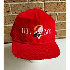 a red hat sitting on top of a white table next to a brick wall with the word, oll m o