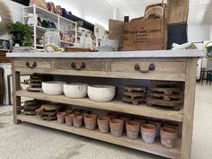 an old wooden table with lots of pots and pans on it's shelf