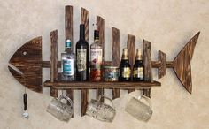 a wooden fish shaped shelf with wine glasses and liquor bottles on it, hanging from the wall