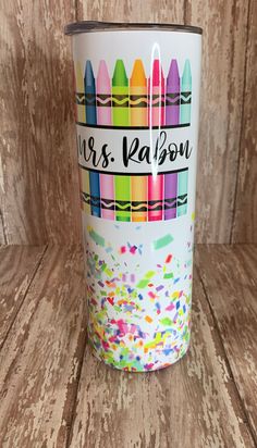 a white cup with colorful crayons and the words mrs ralbow on it