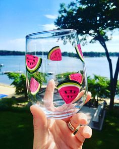 a person holding up a wine glass with watermelon slices on the inside and outside