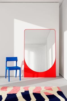 a room with a chair, mirror and rug on the floor in front of it