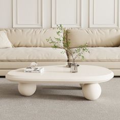 a white coffee table sitting in front of a couch with a plant on top of it