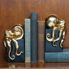 two golden octopus bookends sitting on top of bookshelves next to each other