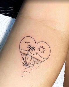 a heart shaped tattoo with two palm trees and a beach ball on the inside of it