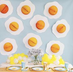 a table topped with plates and bowls filled with breakfast foods on top of a blue wall