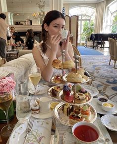 a woman sitting at a table covered in plates and cups with food on top of it