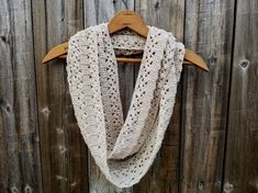 a white crocheted scarf hanging on a wooden fence