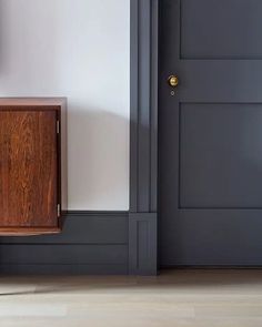 a wooden cabinet sitting in the corner of a room next to a door with a clock on it