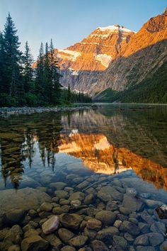 the mountains are reflected in the still water of this mountain lake, which is surrounded by rocks and pine trees