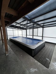 an indoor hot tub in the middle of a room with glass walls and wood flooring