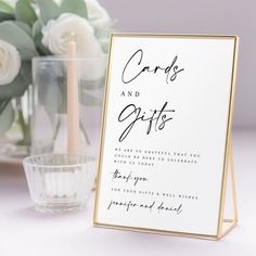 a card and gifts sign sitting on top of a table next to a vase with flowers