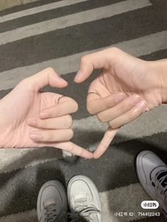 two people holding their hands together in the shape of a heart with one person's fingers