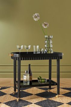 a black table with wine glasses and bottles on it in front of a green wall