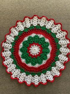 a crocheted doily with a green, red and white circle on it